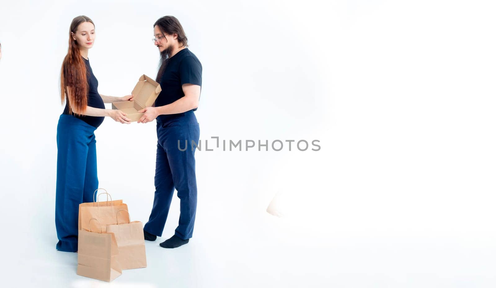 Portrait happy young pregnant woman and her husband with shopping bags and touching her big belly isolated on white background. Pregnancy shopping concept happy young family with shopping bags