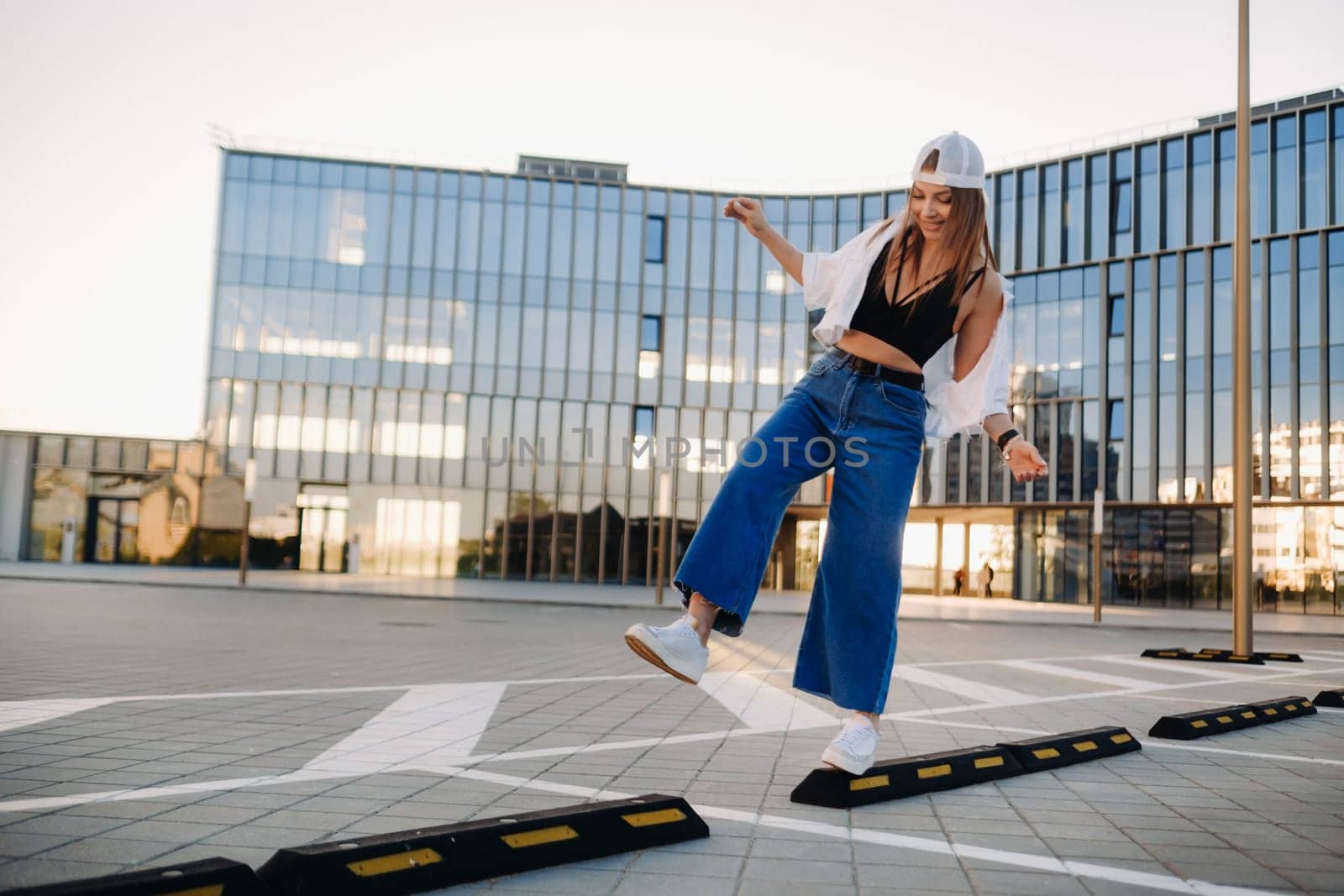 A young teenage girl in jeans and a cap walks around the city by Lobachad