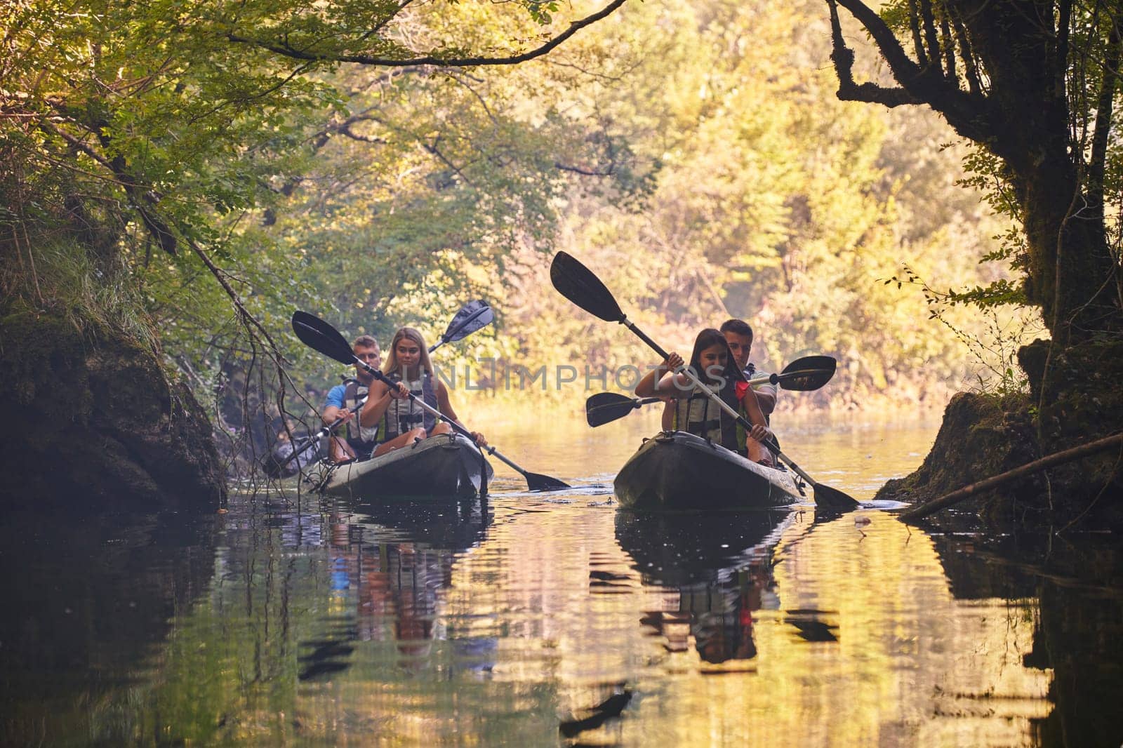 A group of friends enjoying having fun and kayaking while exploring the calm river, surrounding forest and large natural river canyons.