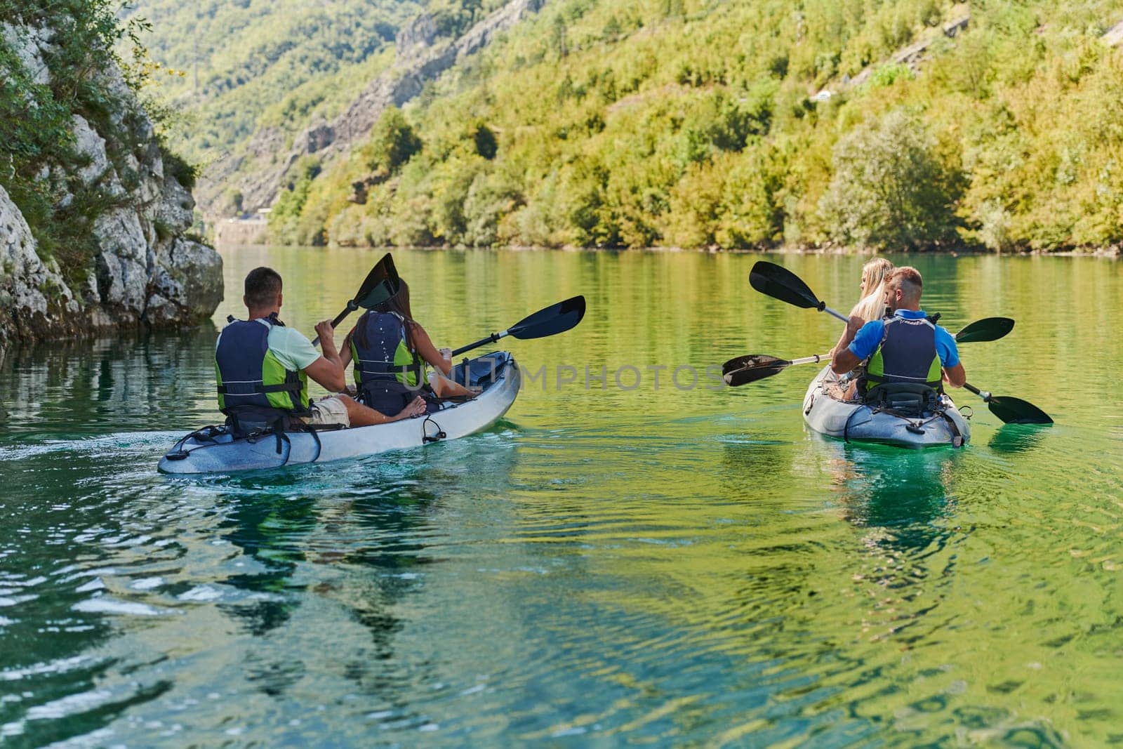 A group of friends enjoying having fun and kayaking while exploring the calm river, surrounding forest and large natural river canyons.