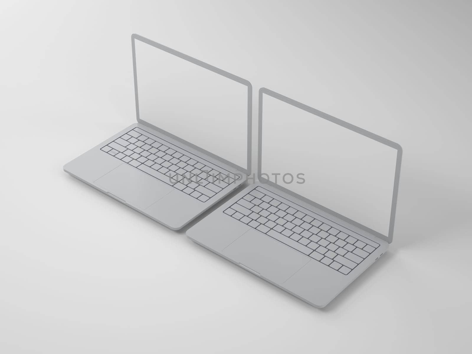 Two open modern gray laptops with blank screens on a light background