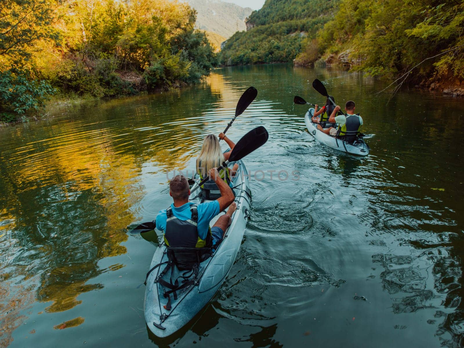 A group of friends enjoying having fun and kayaking while exploring the calm river, surrounding forest and large natural river canyons.