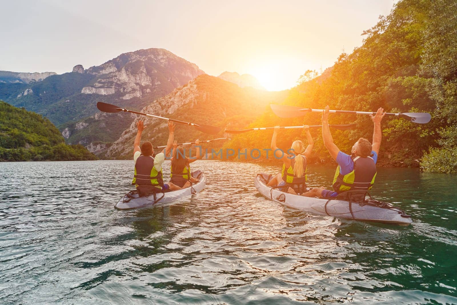 A group of friends enjoying fun and kayaking exploring the calm river, surrounding forest and large natural river canyons during an idyllic sunset