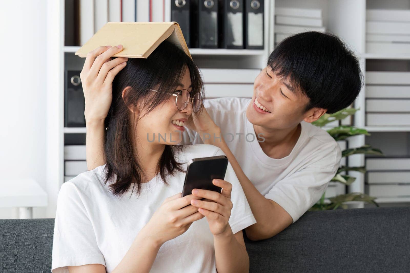 Relax, home couple on a couch, mobile phone and happiness with social media and connection. man and woman on a sofa, technology and loving with a smile, romance and reading.
