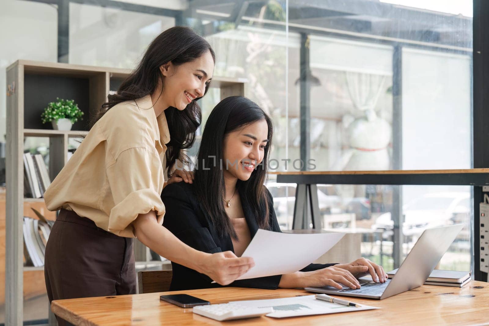 Business people women analyzing documents while sitting on a table in office. Woman executives at work in office discussing some paperwork.