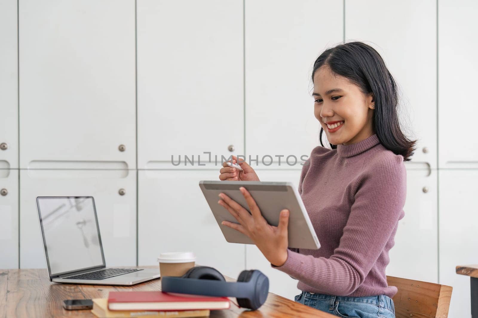 Asian girl college student taking online training class on digital tablet and laptop sitting at university table. Virtual education webinar, remote study, distance academic learning.