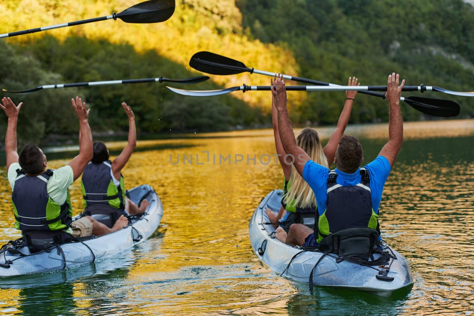 A group of friends enjoying having fun and kayaking while exploring the calm river, surrounding forest and large natural river canyons by dotshock