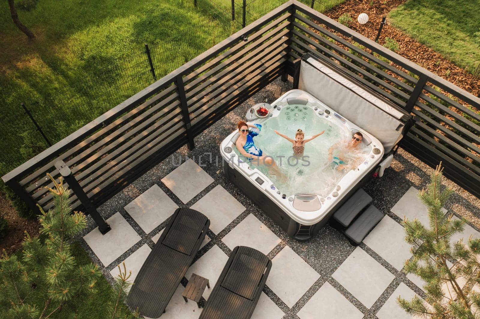 Top view of a family relaxing in an outdoor hot tub in summer by Lobachad