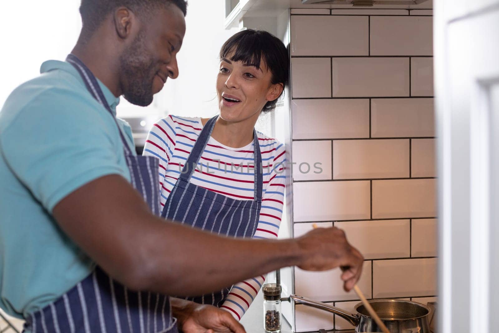 Happy multiracial young couple cooking food together at home by Wavebreakmedia