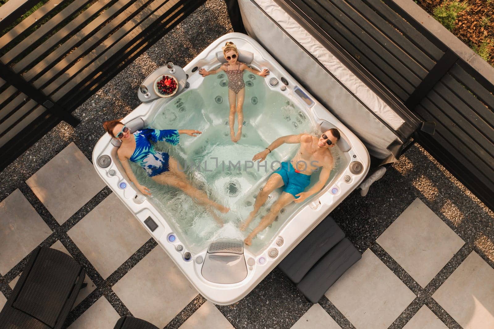 Top view of a family relaxing in an outdoor hot tub in summer by Lobachad