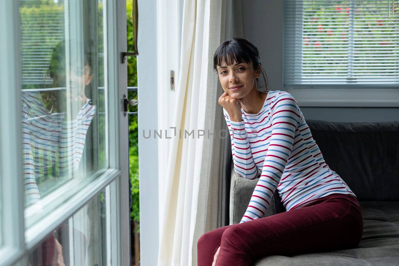 Portrait of caucasian young woman sitting by window at home. unaltered, lifestyle, domestic life, leisure.