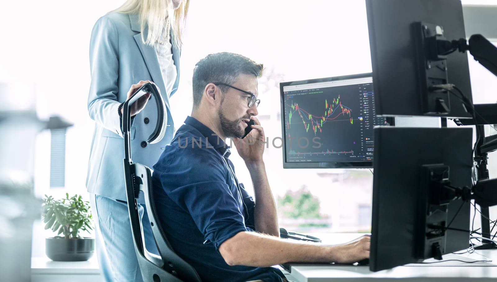 Stock broker business team trading online watching charts and data analyses on multiple computer screens in modern corporate work station office