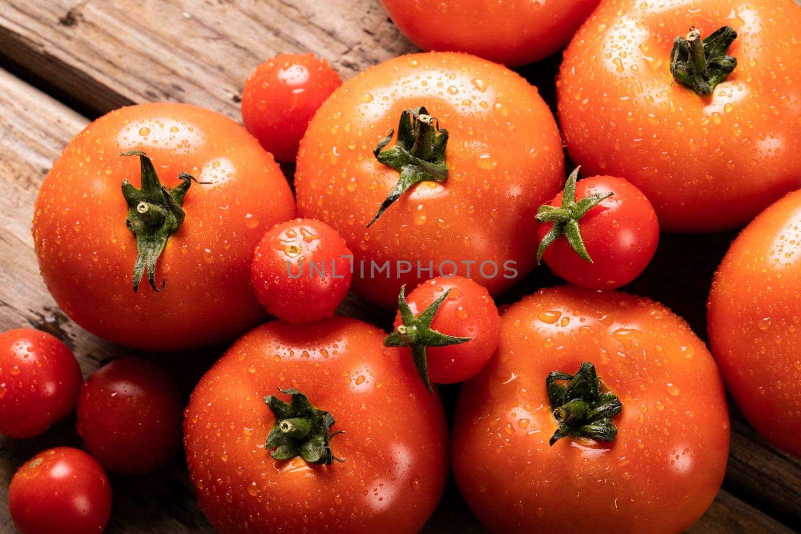 Directly above view of fresh red tomatoes with water drops on table by Wavebreakmedia