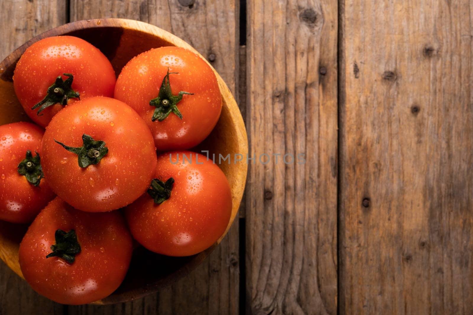 Directly above view of fresh red tomatoes with water drops in plate on wooden table. unaltered, organic food and healthy eating concept.