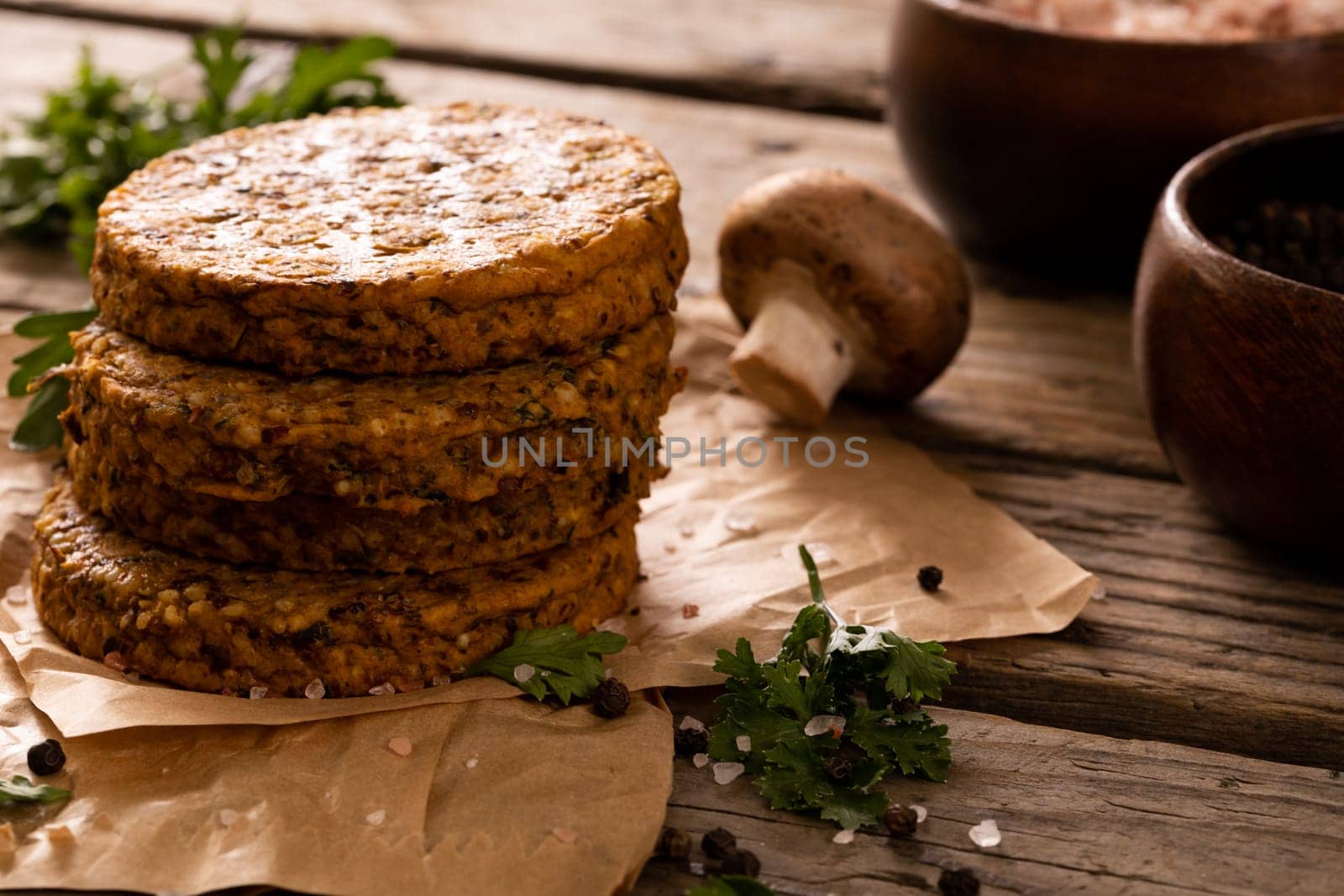 Close-up of patties stacked by edible mushroom on wooden table by Wavebreakmedia