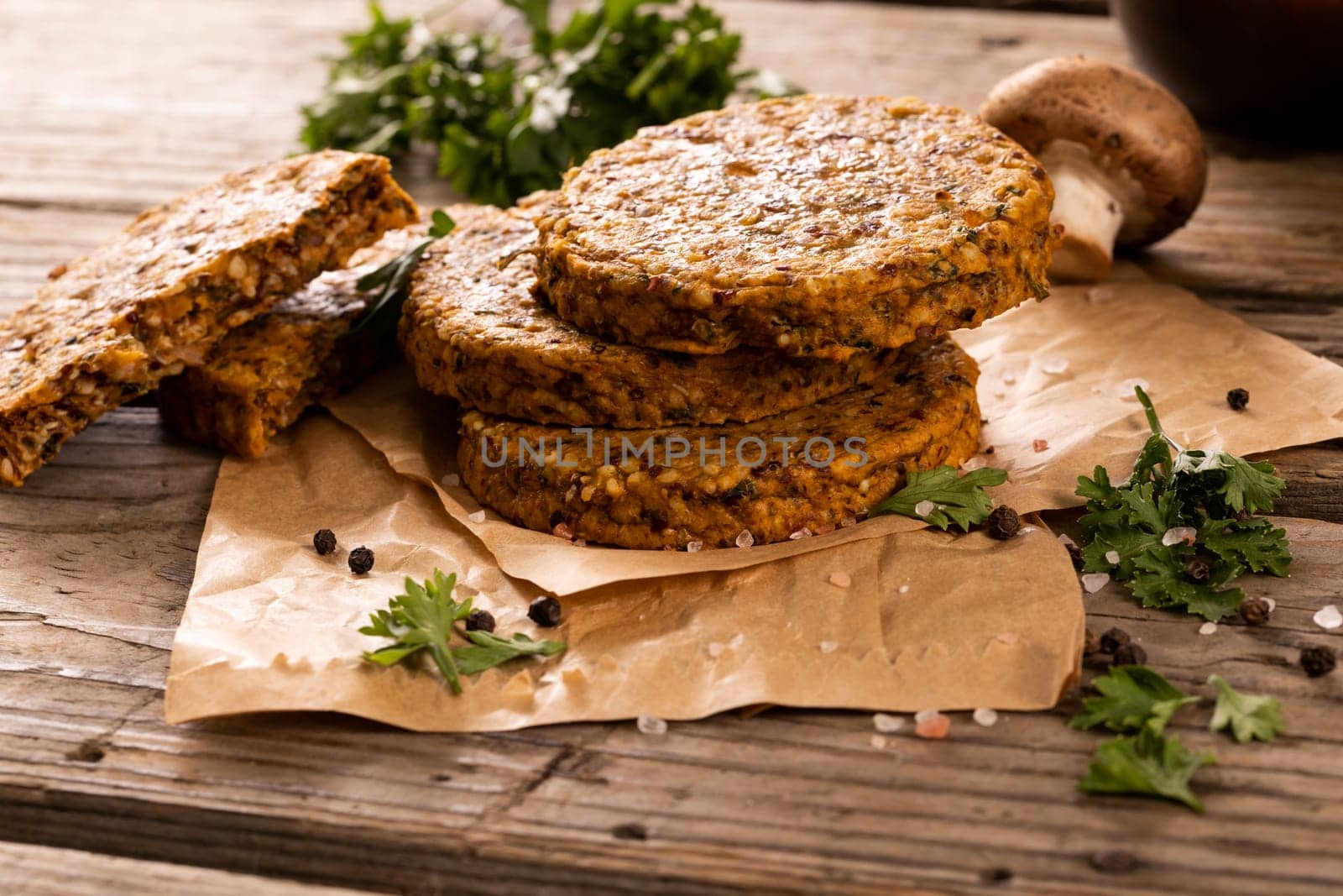 High angle view of stacked fresh patties with seasoning on wax paper over wooden table by Wavebreakmedia