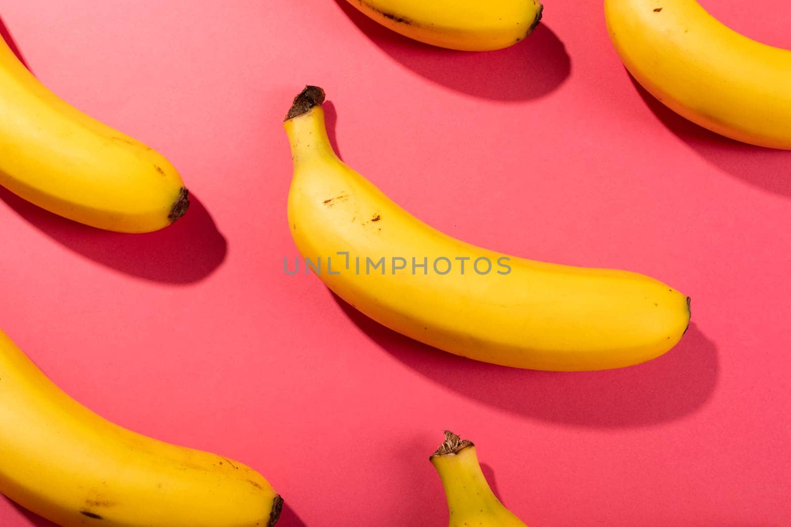 Overhead view of fresh bananas on pink background. unaltered, organic food and healthy eating concept.
