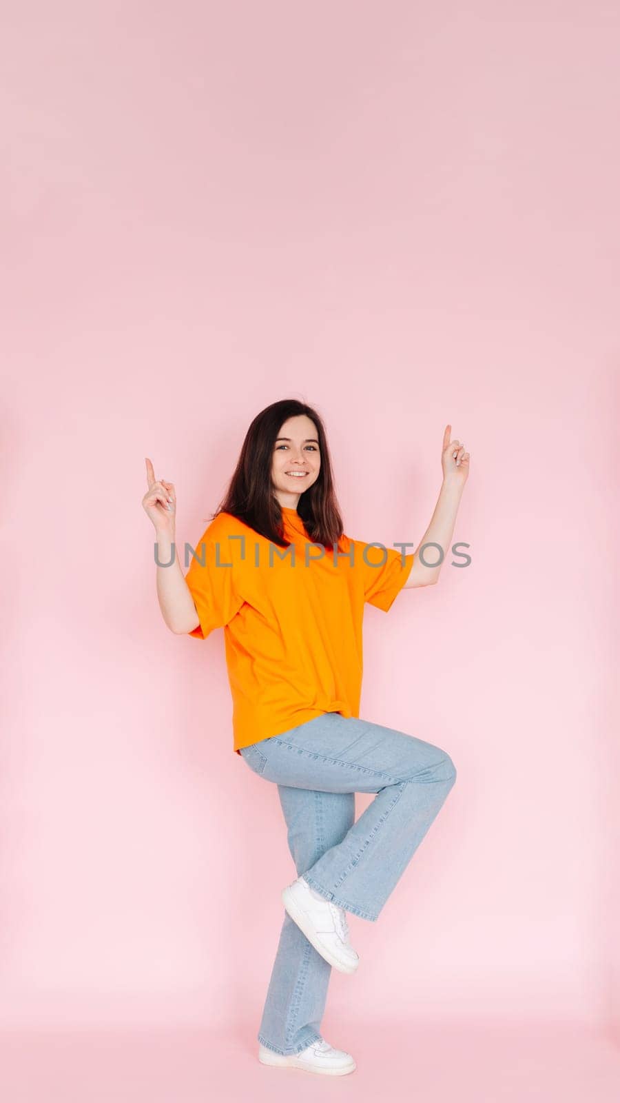 Celebratory Success: Beautiful Young Woman with Fists Raised in Joyous Victory, Marking the Completion of a Contract - Honoring a Lucrative Sales Promotion on Pink Background.