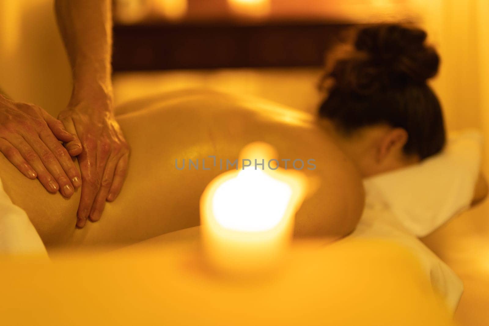 Massage session - massaging lower back of a woman in SPA salon. Mid shot