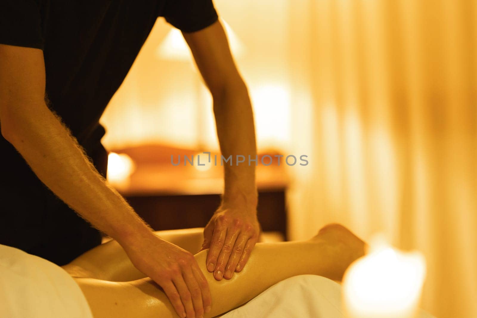 Massage in spa salon - a man massages the shin of his female client. Mid shot