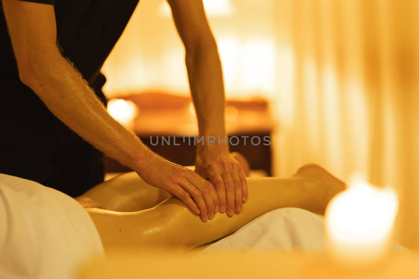 Massage in spa salon - a man massages the shin of a woman client. Mid shot
