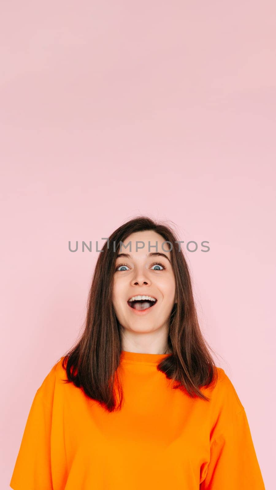 Energetic Expression: Impressed and Cheerful Woman with Open Mouth - Vibrant Emotion and Enthusiasm Captured on Pink Background