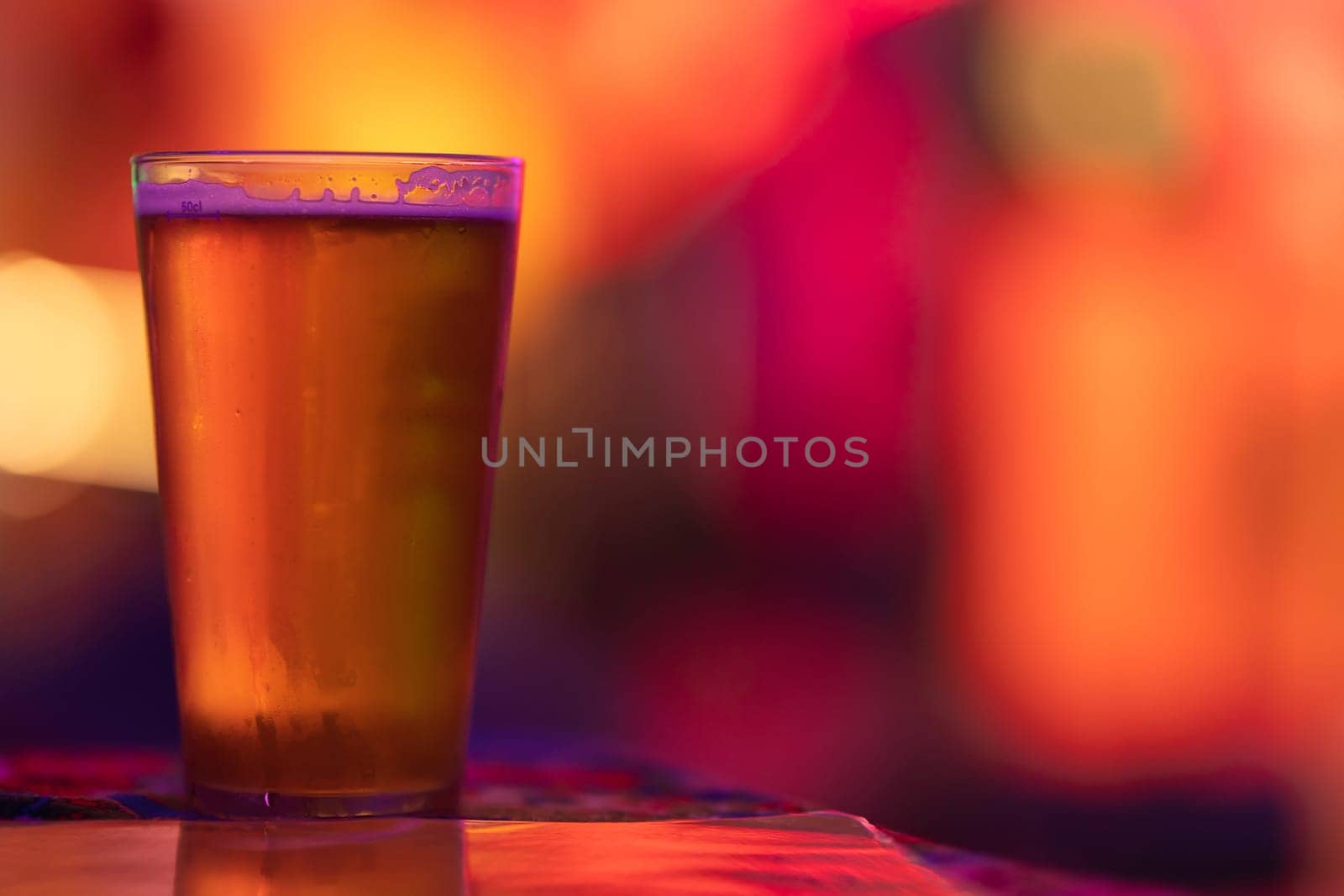 A glass of beer on the bar in a bright colorful setting. Mid shot