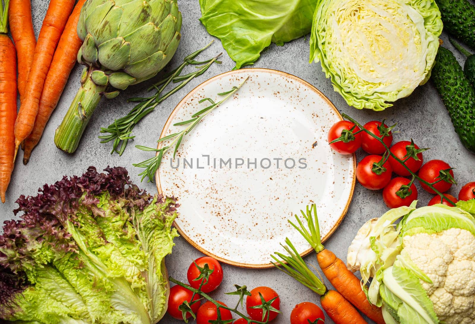 Assorted food raw products: vegetables, beef meat, fish salmon and empty plate in centre, light rustic stone table top view copy space. Healthy food background, ingredients for balanced diet.