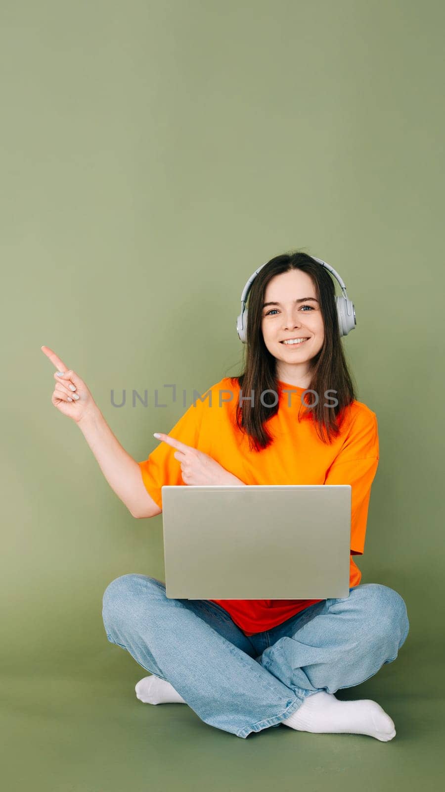 Young professional woman confidently working on laptop, pointing to empty space for text and advertising. Isolated on green background. Perfect for business and technology concepts. by ViShark
