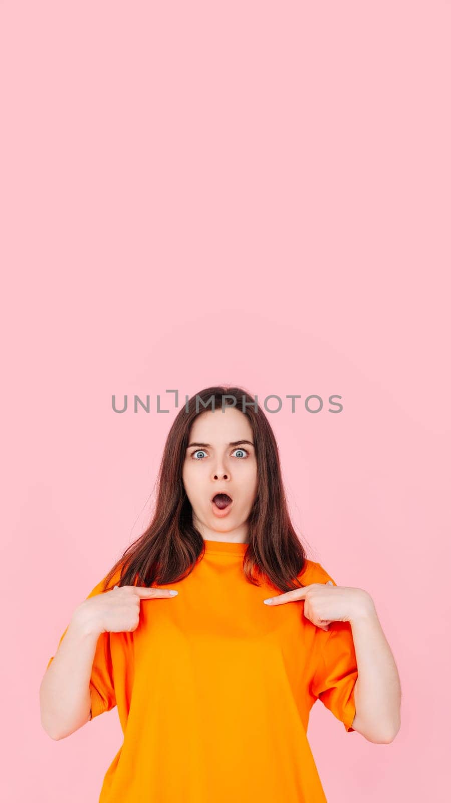 Young Woman Pointing at Herself in Amazement, Expressing Belief in Winning the Competition. Positive Image of Self-Assurance and Determination. Isolated on Pink Background for Impactful Visuals