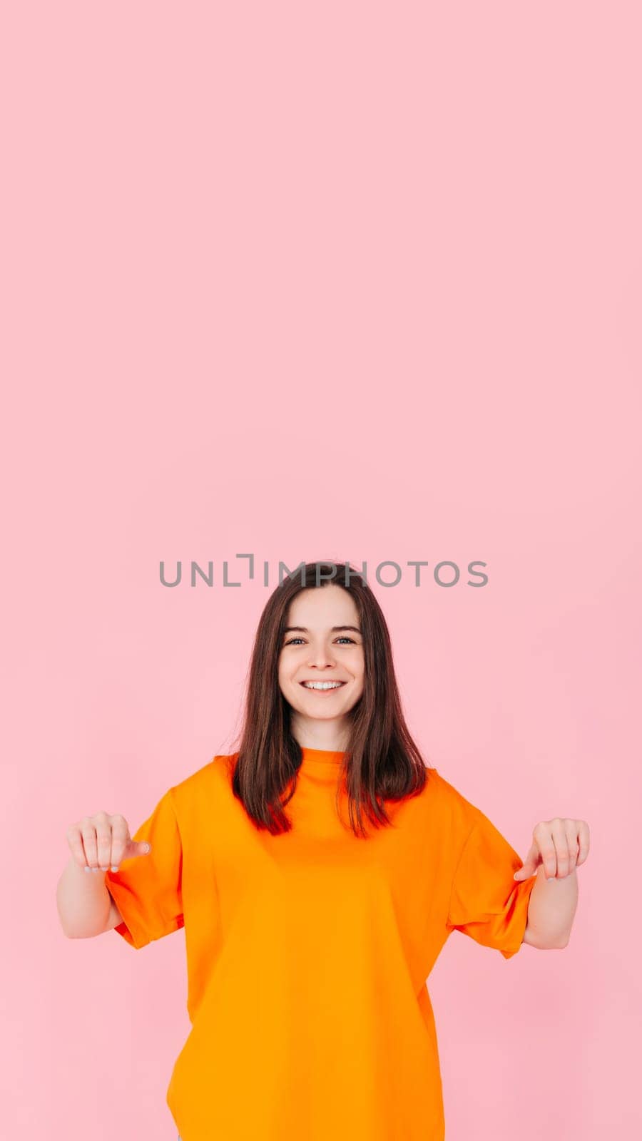 Surprised Woman Holding White Promo Paper for Unexpected Best Deal Offer. Expressive Shock and Excitement. Isolated on Pink Background. Perfect for Advertising, Marketing, and Promotional Concepts.