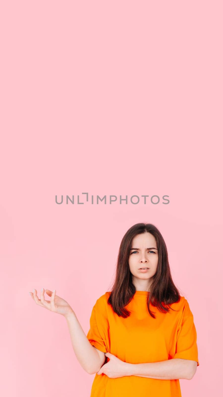 Frustrated Woman Expressing Anger and Discontent in Vibrant Attire. Isolated on Pink Background. Suitable for Concepts of Emotions, Frustration, Disappointment, and Negative Reactions