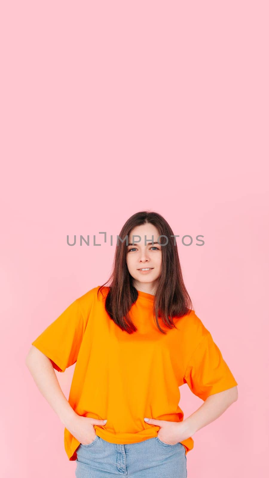 Joyful and Charming Young Woman with a Radiant Smile, Hands in Pockets. Contentment and Happiness. Isolated on Pink Background. Perfect for Lifestyle, Happiness, and Positive Vibes Concept by ViShark