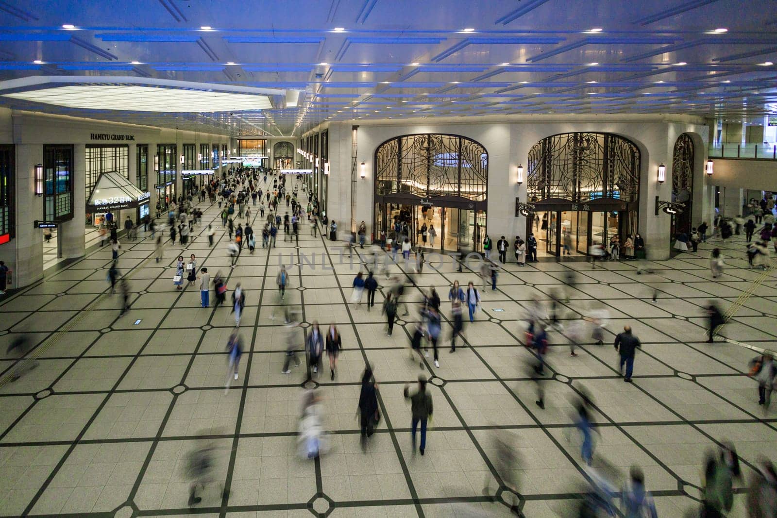 Osaka, Japan - April 6, 2023: Pedestrians blur in covered walking arcade by Umeda Station by Osaze