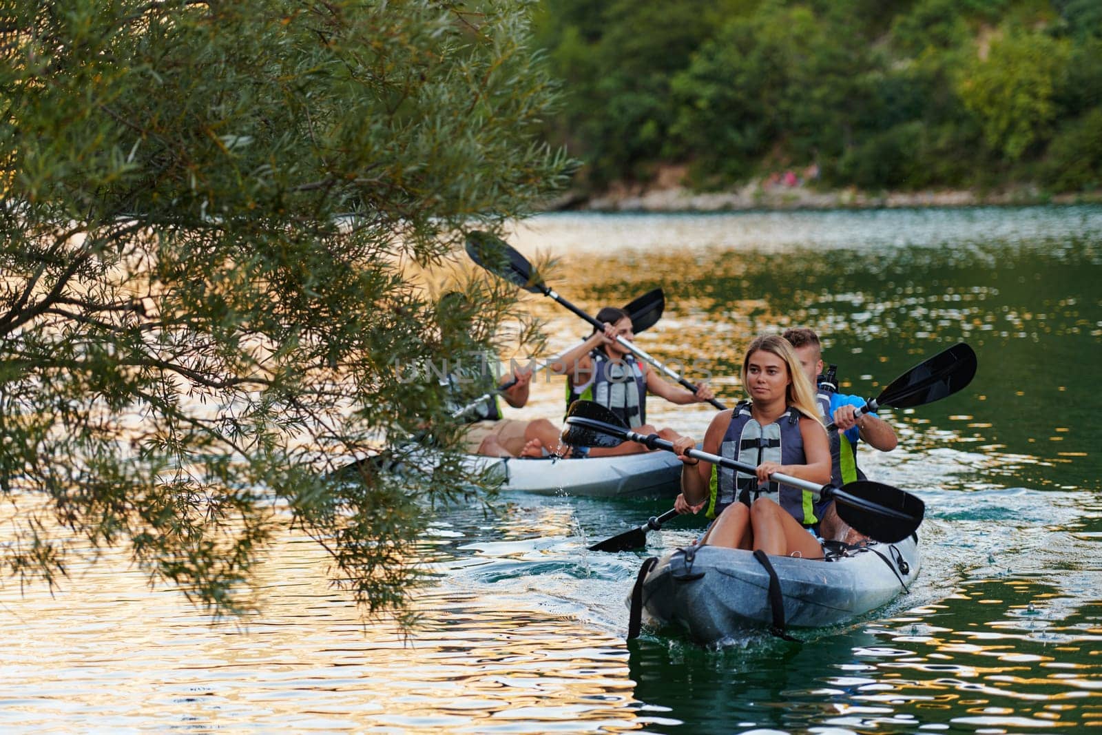 A group of friends enjoying having fun and kayaking while exploring the calm river, surrounding forest and large natural river canyons by dotshock