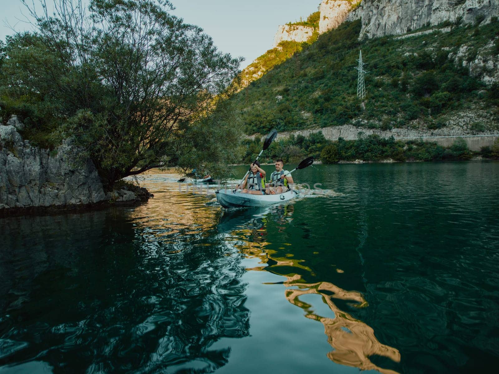 A group of friends enjoying having fun and kayaking while exploring the calm river, surrounding forest and large natural river canyons by dotshock