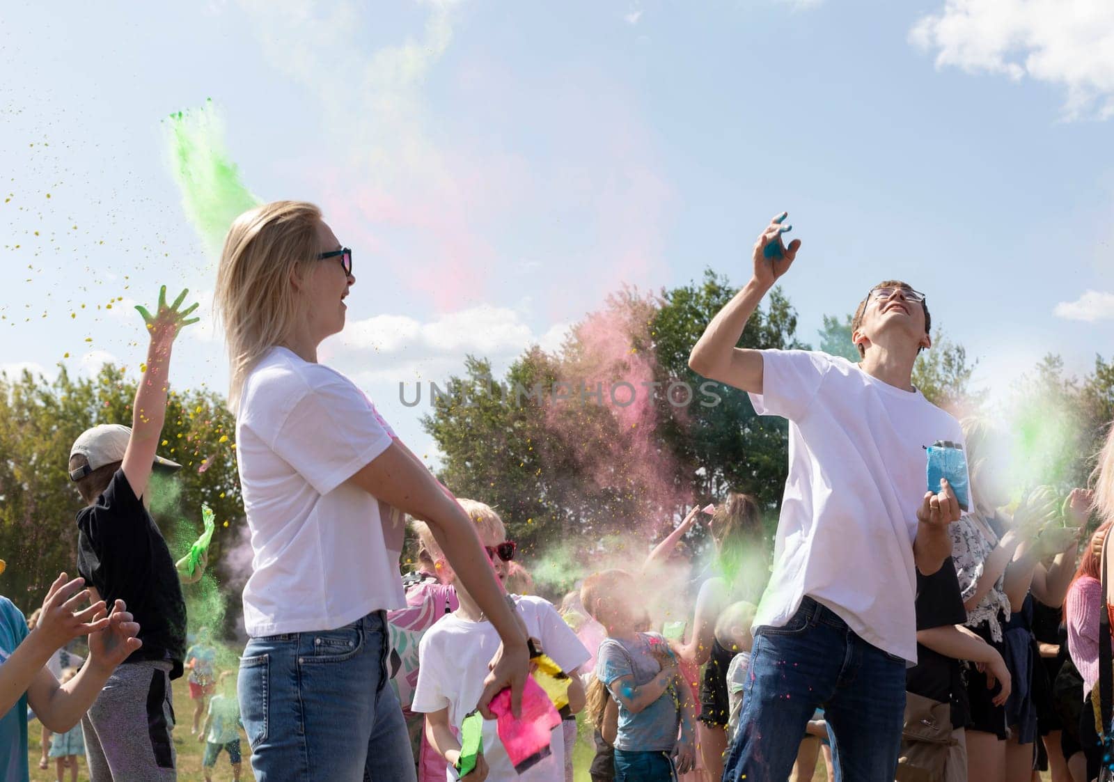 Caucasian Adults And Children Celebrate Holi Color Festival, Throwing Colored Dye In Air. Group Of Kids, Parents Playing With Paint Outdoor In Park. Birthday, Cheerful Family Activity.Horizontal Plane by netatsi
