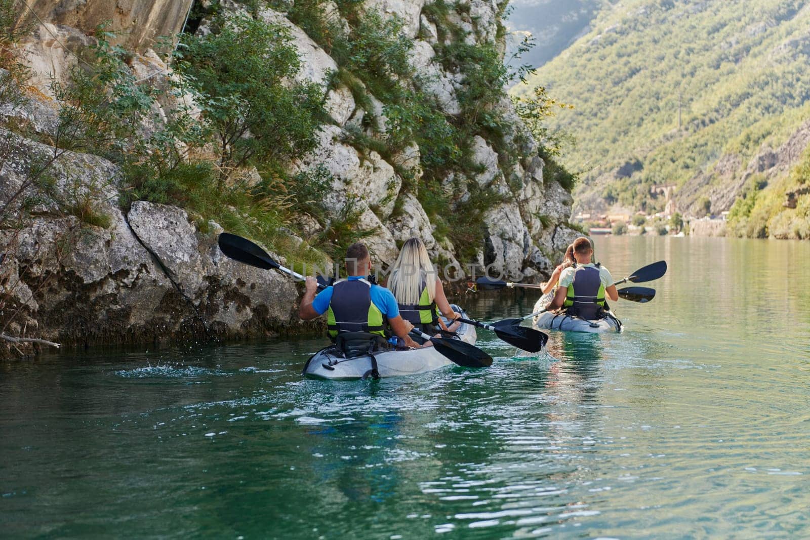 A group of friends enjoying having fun and kayaking while exploring the calm river, surrounding forest and large natural river canyons.