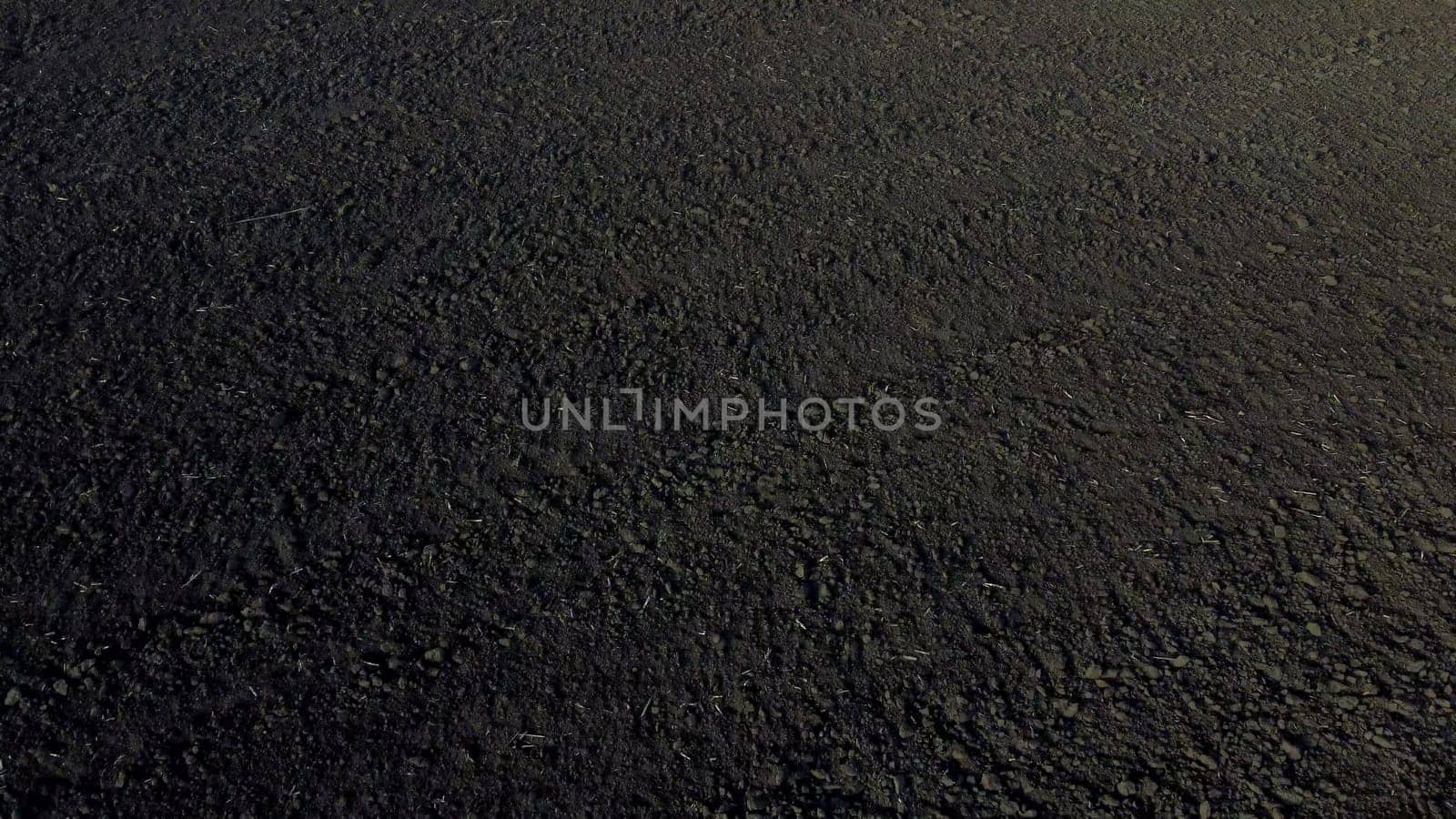 Landscape of plowed up land on agricultural field on sunny autumn day. Ground earth dirt priming. Flying over plowed earth with black soil. Black soil. Agrarian background. Aerial drone view.