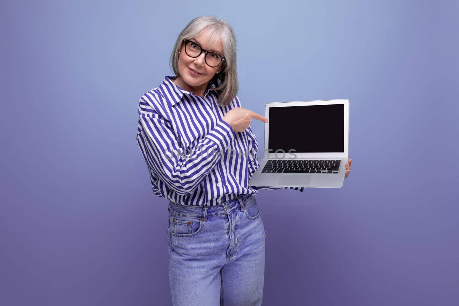 modern pensioner woman learning new profession using laptop with mockup on bright studio background.