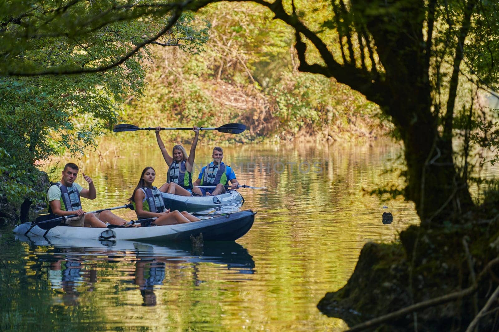 A group of friends enjoying having fun and kayaking while exploring the calm river, surrounding forest and large natural river canyons.