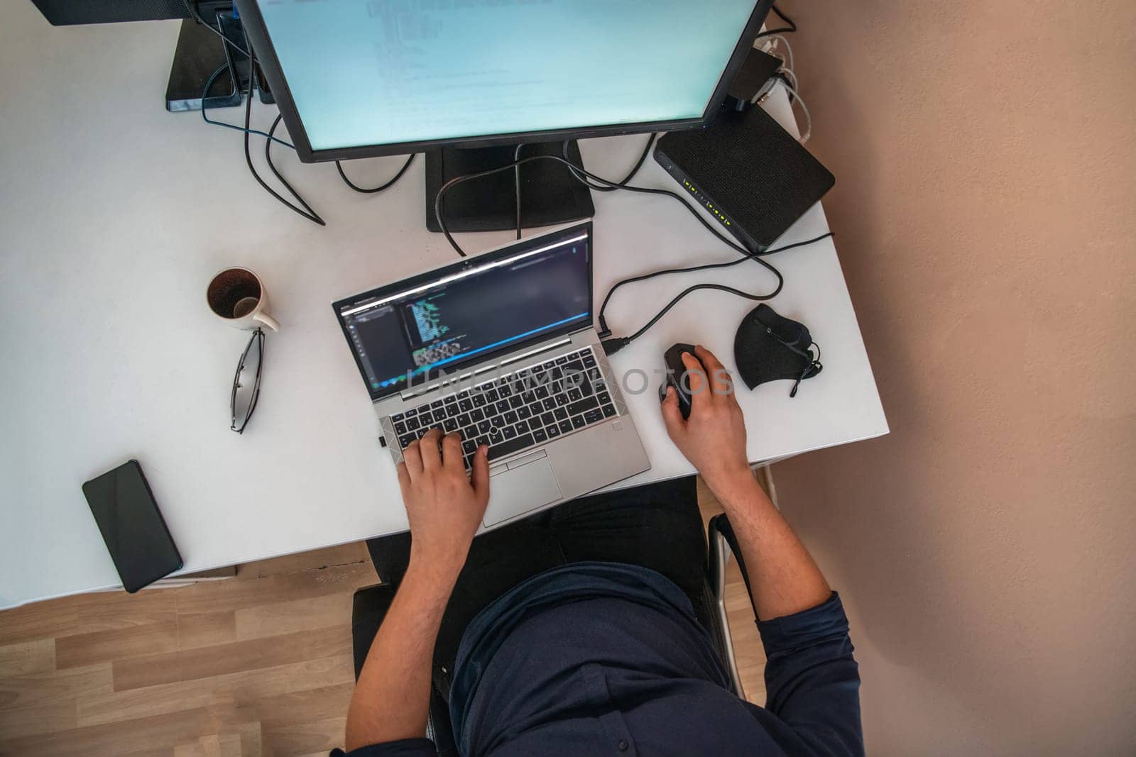 Top view of programmer diligently testing smartphone applications while sitting in their office. by dotshock