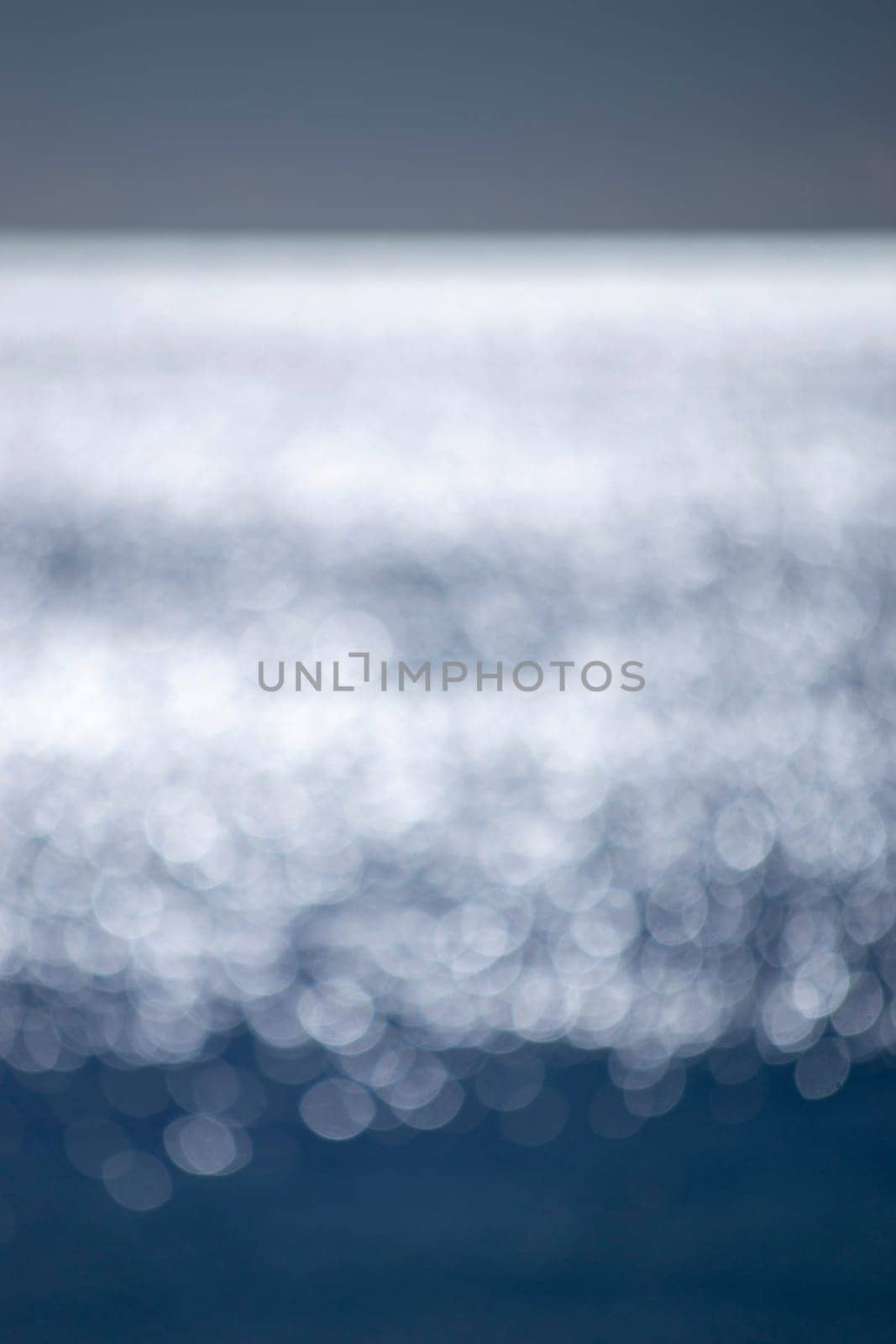 Abstract blurred background.Spots of white reflections of shining sun on blue surface of sea waves.Sea on sunny day.Natural blurry bokeh texture backdrop.Seamless looping.Beautiful natural background