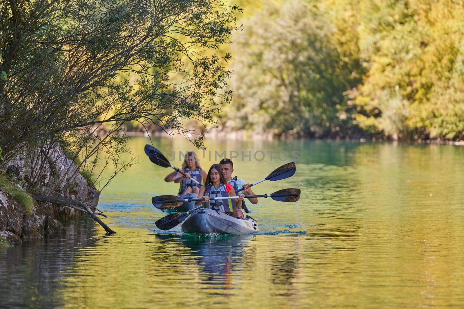 A group of friends enjoying having fun and kayaking while exploring the calm river, surrounding forest and large natural river canyons.