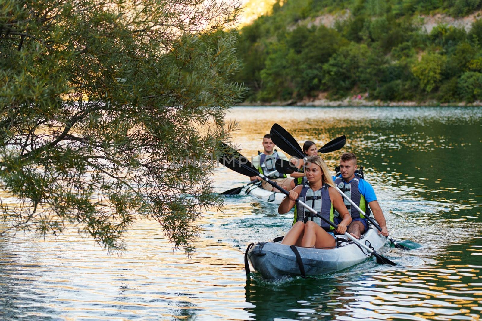 A group of friends enjoying having fun and kayaking while exploring the calm river, surrounding forest and large natural river canyons.