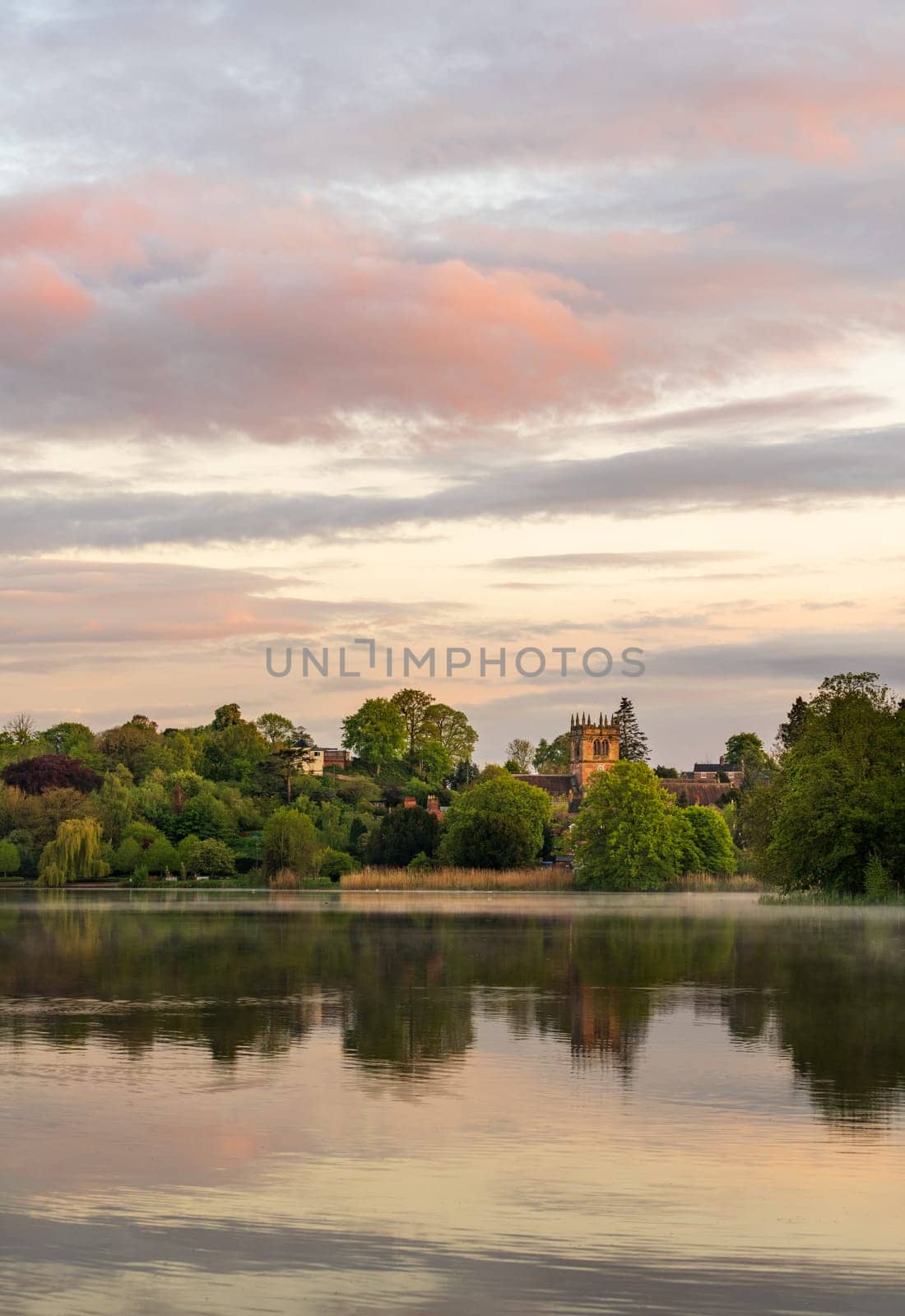 Sunset view across Ellesmere Mere in Shropshire to church by steheap