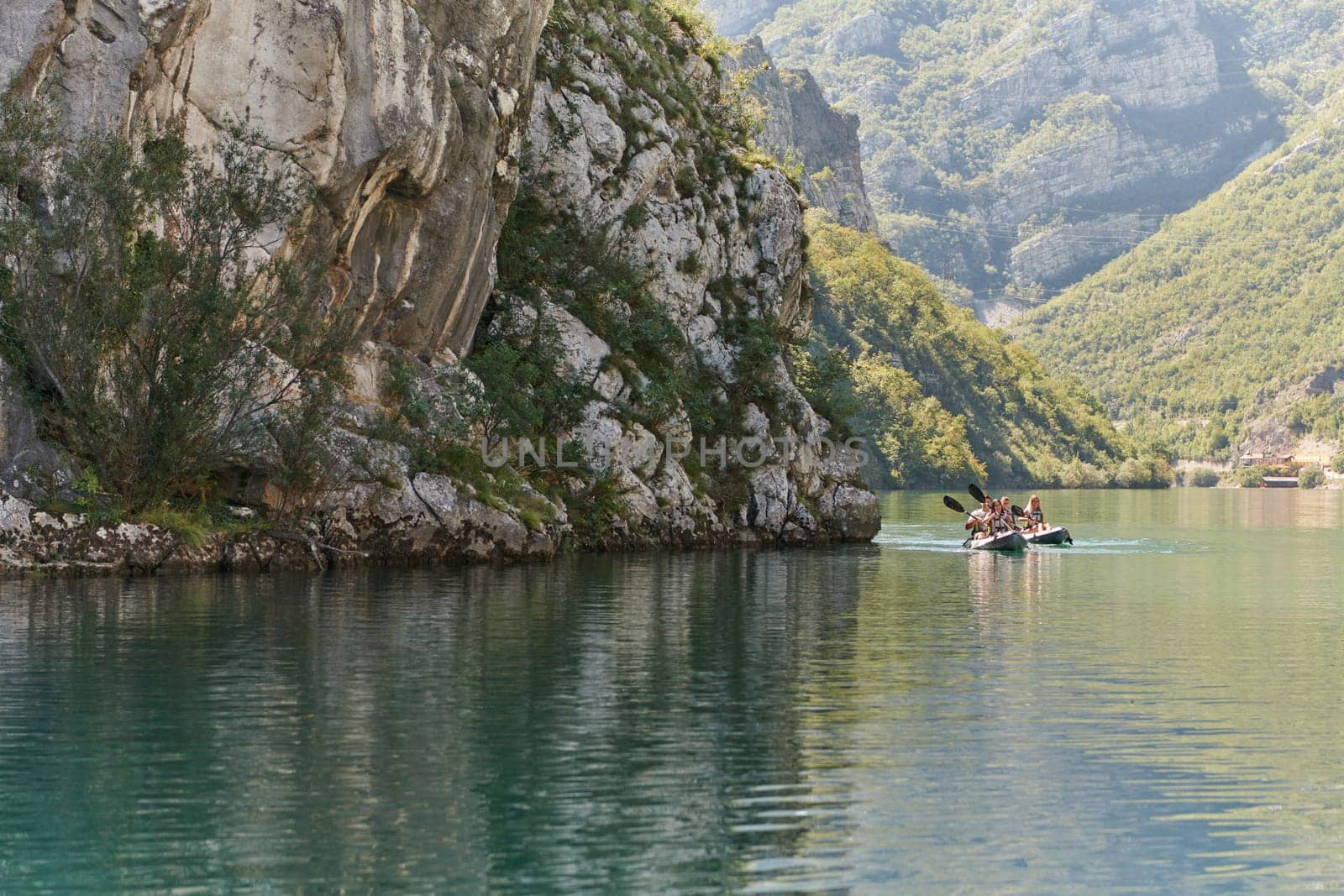 A group of friends enjoying having fun and kayaking while exploring the calm river, surrounding forest and large natural river canyons.