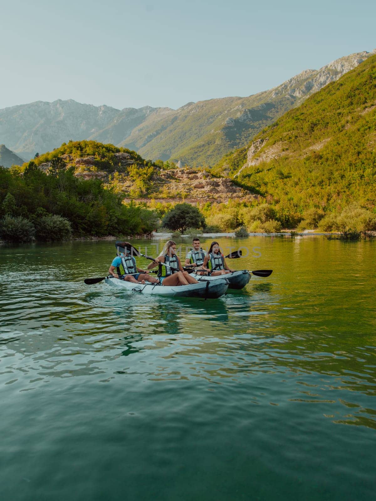 A group of friends enjoying having fun and kayaking while exploring the calm river, surrounding forest and large natural river canyons by dotshock