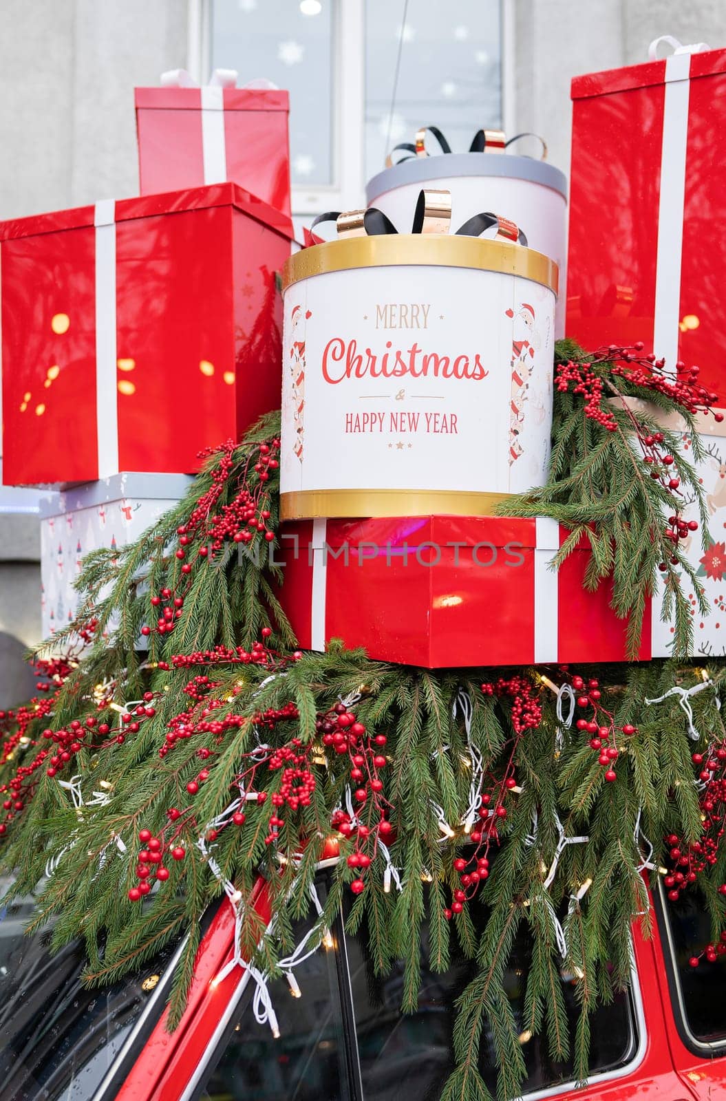 Against the background of a Christmas tree and decorations, there are many large, bright and beautiful red gift boxes. Christmas and New Year 2023-2024