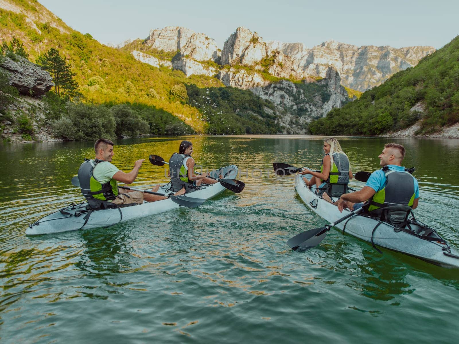 A group of friends enjoying having fun and kayaking while exploring the calm river, surrounding forest and large natural river canyons by dotshock